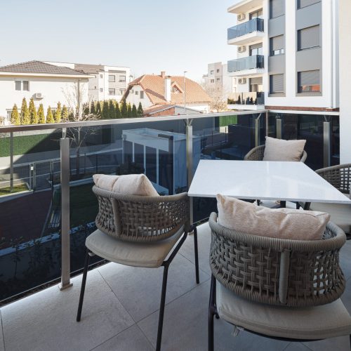 Zemun stan apartment balcony with outdoor furniture and a scenic view of the neighborhood.