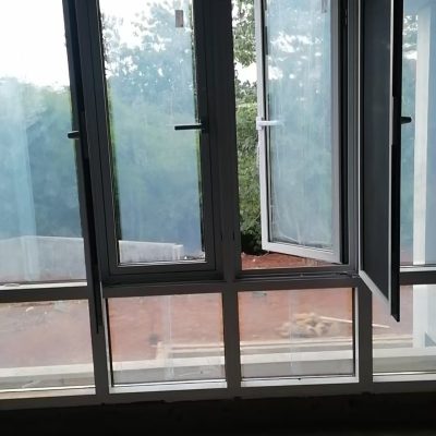 White aluminum window with a screen installed in a luxury villa in Bogor, Indonesia, providing ventilation and insect protection.