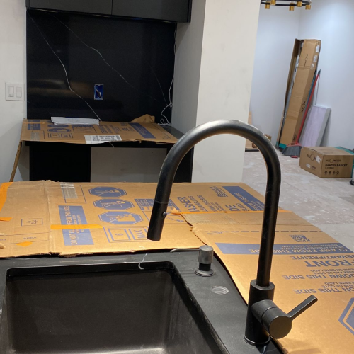 Custom kitchen sink area in Los Angeles with black cabinets and marble countertops.