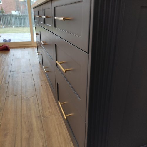 custom kitchen cabinet Canada, modern kitchen sink with stylish gold faucet and marble backsplash.