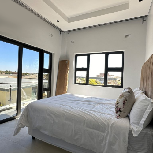 Custom bedroom with large windows, a comfortable bed, and modern finishes in a Zimbabwe full house custom project.