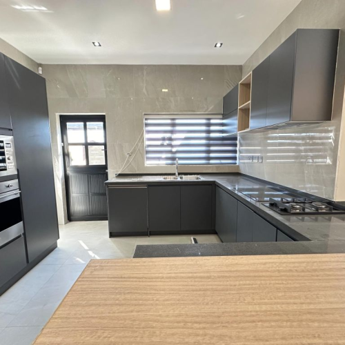 Custom kitchen in a Zimbabwe full house project featuring sleek black cabinetry, high-end appliances, and a central island.